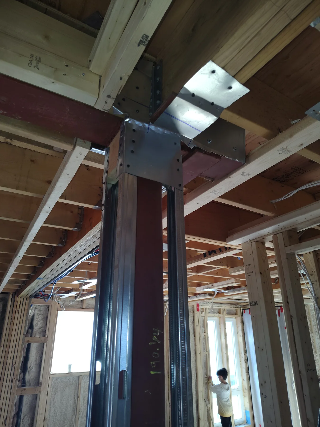 Steel post supporting a structural beam within wood framing